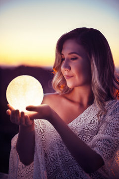 Romantic evening capture during sunset over Tirana where a girl is holding the Moon in her hands.