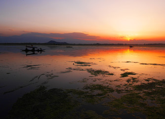 Colorful sunset at Dal Lake in Kashmir, India with a single boat in the side of the lake