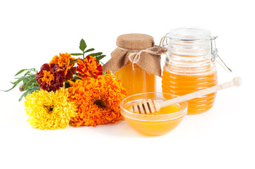 Natural honey in jar and dipper with flowers on a white background
