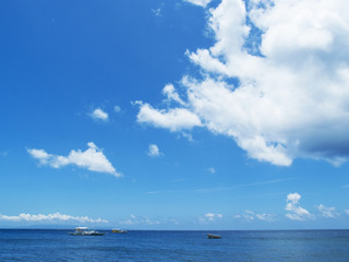 Sea water landscape with blue sky and ripples. Seashore view with white boats.