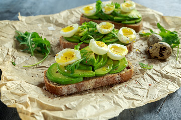 Healthy Avocado and quail eggs toasts with wild rocket and sea salt