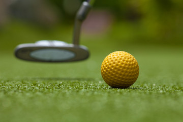 golf club and yellow ball on artificial grass