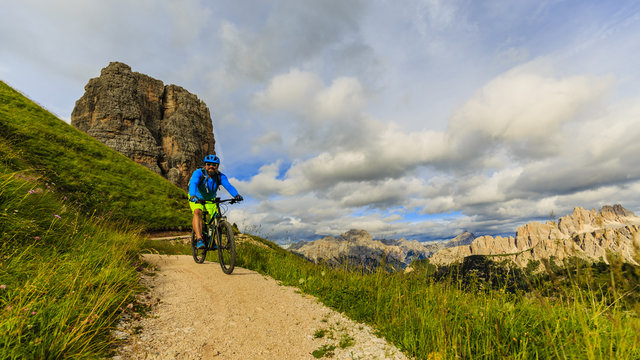Cycling, View of cyclist riding mountain bike on single trail in Dolomites, Cinque Torri, South Tirol, Italy