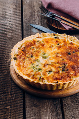 Quiche Lorraine with chicken and vegetables on rustic dark table background. Pie with mushrooms, chicken and broccoli on wooden kitchen board. Traditional French food.