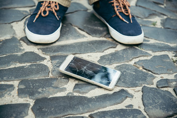 cracked smartphone screen near legs