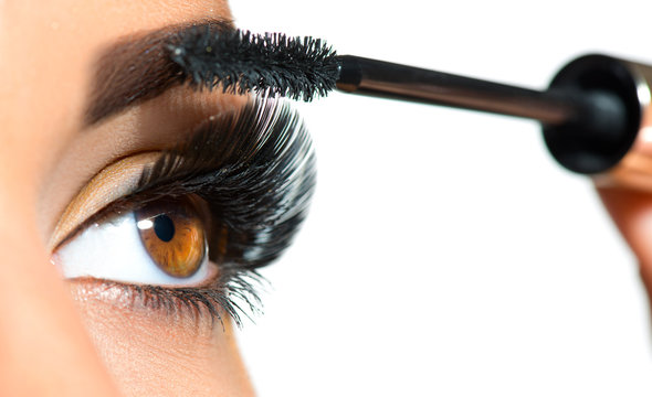 Long lashes closeup. Beautiful woman applying mascara on her eyes. Makeup