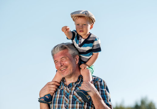 Grandfather Carries Grandson Toddler Boy On His Shoulders