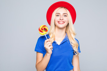 Glamourous girl wearing heart shaped sunglasses holding lollipop over gray background