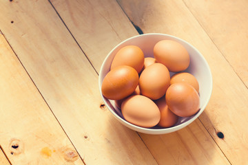 A bowl of eggs on wood table.
