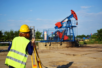 A female engineer - land surveyor at work on an European oil well