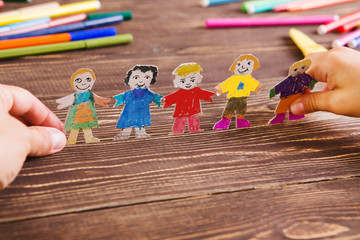 the child does figures of people of paper. Paper people on wooden background. Creative child play...