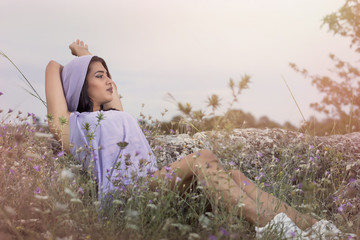 Brunette young girl posing outdoor in a field of wild flowers
