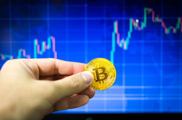 Man holding gold bitcoin and BTC trading chart in background, Financial concept