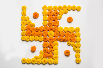 stock photo of hindu auspicious symbol called Swastika made using marigold flower or zendu or genda phool, Flower rangoli in the shape of Swastika for diwali/pongal/onam over white background
