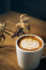 Fresh coffee latte art in white cup on wooden table.
