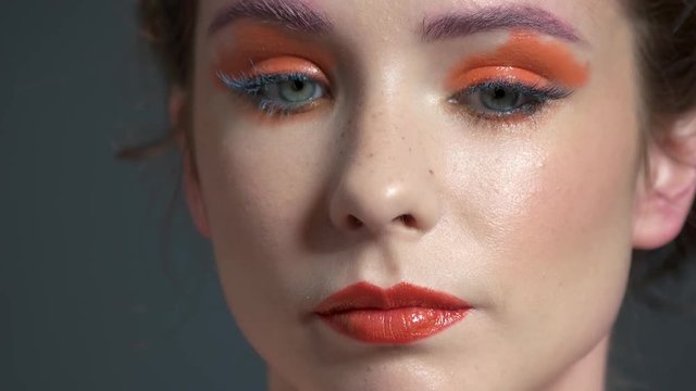 Hand of visagist, eyeshadow brush. Young woman, colorful makeup.