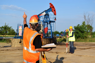 Two engineers - land surveyors at work on an European oil well 
