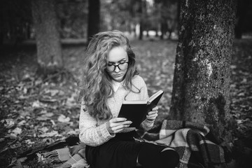 redhead girl reading the book in autumn park