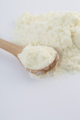 Closeup of powdered milk and a wooden spoon.