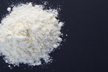 Heap of powdered milk on the black background.
