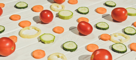 Multicolored slicing vegetables on a white wooden board background