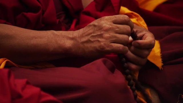 Buddhist monk praying - hands and beads rosary closeup