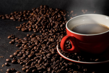 Hot coffee in red cup and coffee beans are the background.