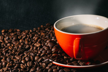 Hot coffee in red cup and coffee beans are the background.