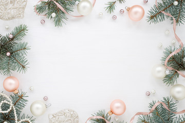 Holidays frame of new year`s decorations on white background. Fir branches, balls, ribbon and pearls, pastel colors