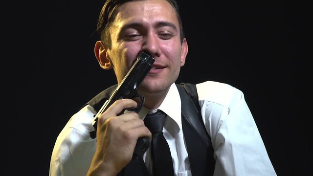 A detective in a suit shoves the muzzle of the pistol into his nostril