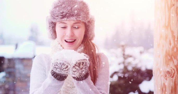 Blowing Snow, SLOW MOTION 120fps 4K DCi. Beautiful Joyful Female Model having fun near wooden log Cottage. Young woman enjoying magical snowfall. Winter wonderland. Snow Day near Mountain Chalet Cabin