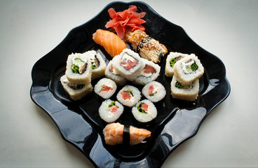 sushi rolls in a black ceramic plate isolated on white
