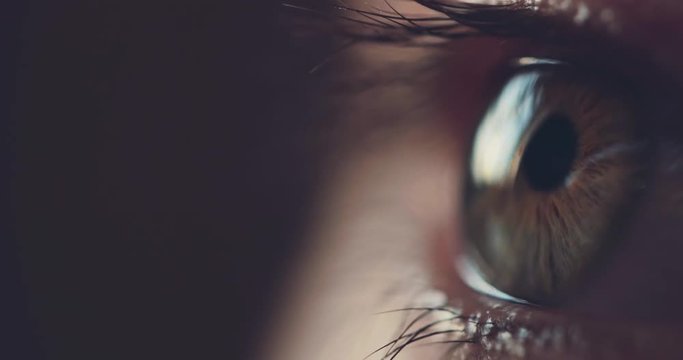 Macro Close-up Eye Blinking. SLOW MOTION 4K DCi. Young Woman is opening and closing her hazel eye. Eyesight health. Cinematic close up shot on dark background.