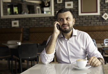 Handsome man talking on the phone in cafe