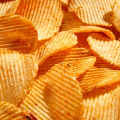 background of crispy golden chips with ribbed texture, seasoned, with sunlight. Frame for...