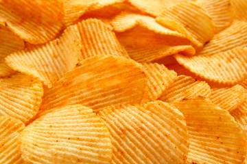 background of crispy golden chips with ribbed texture, seasoned, with sunlight. Frame for...
