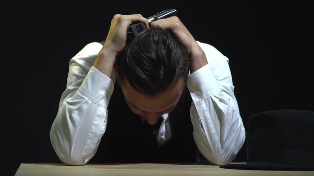 Tired detective in a suit with a gun sits at the table
