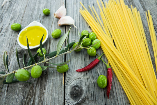 Ingredients for cooking Italian pasta - spaghetti oil, garlic and chili on a rustic wooden background