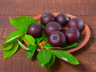Ripe plums on a clay plate.