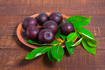 Ripe plums on a clay plate.