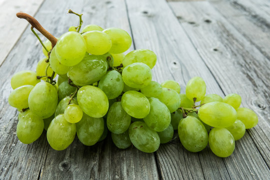 bunch of ripe and juicy green grapes close-up on a wood background