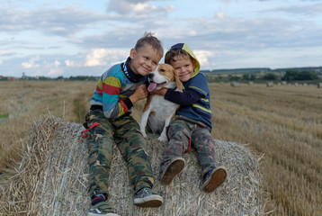 two boys and a Beagle on a bale of straw