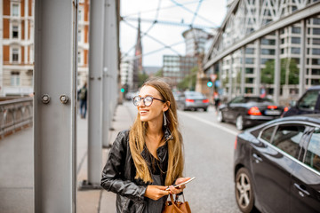 Obraz premium Lifestyle portrait of a stylish businesswoman on the old iron bridge in Hamburg, Germany