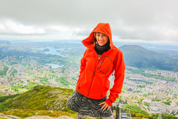 Happy tourist after hiking on Mount Ulriken. Norwegian tourism highlight. Bergen city skyline in Norway. Traveler woman in North Europe. Scenic norwegian landscape and popular landmark.