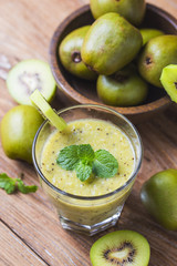 glass of kiwi juice with fresh fruits on wooden table