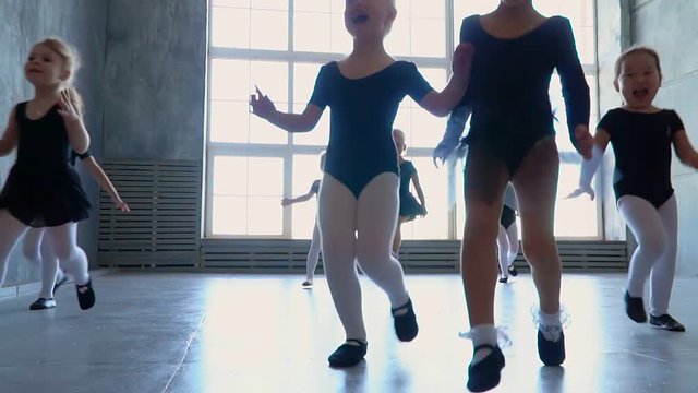 Children from ballet school run in embraces of the teacher of the ballerina. Little girls of the ballerina run to embrace the teacher