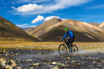 Fototapeta premium A man is riding a bicycle in the mountains. Autumn in the mountains Kyrgyzstan. Burkan River Valley