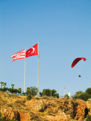 Person paragliding near Turkish flag in Antalya, Turkey