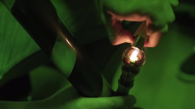 Smoking cannabis through a glass bong close-up . Ignition of buds of marijuana in a bong 