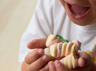 the child holds a handful of marshmallows